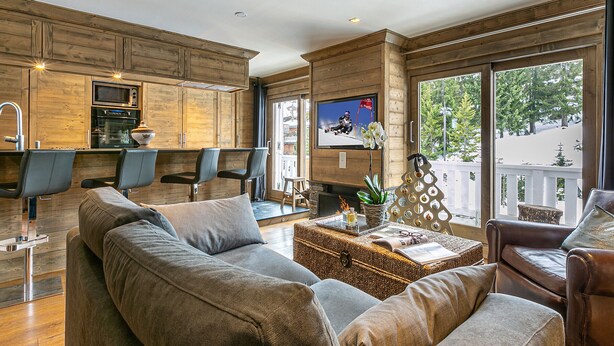 Ein modernes Wohnzimmer mit einer großen Eckcouch, einem Couchtisch und einem an einer Holzwand montierten Fernseher.