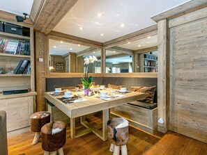 Un comedor con una mesa de madera, sillas y una estantería.