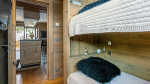 A compact, wooden interior with bunk beds, a small kitchenette, and a television.