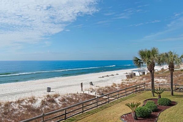 A beach view with a wooden fence, palm trees, and a clear sky. - 🏝️Gulf Views-Small Complex-Polynesian Village 211🏝️ (Panama City Beach)