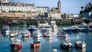 A harbor with multiple boats docked, a prominent clock tower, and residential buildings along the waterfront. - Luxury Cottage with Parking, Minutes to Beach and Restaurants (Porthleven)