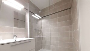 A modern bathroom with a glass-enclosed shower, a white vanity, and a large mirror.