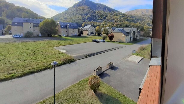 A residential area with multiple buildings, a parking lot, and a mountain in the background.