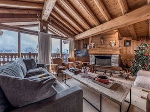 Cozy living room with a fireplace, comfortable seating, and a view of the outdoors.