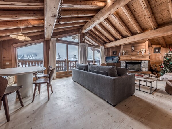 Cozy cabin-style interior with a high ceiling, fireplace, and dining area.