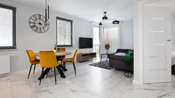 A modern living space with a dining area, a sofa, and a television.