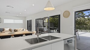 Una cocina moderna con una isla central, una zona de comedor con mesa y sillas, y un ventanal que ofrece vistas al exterior.