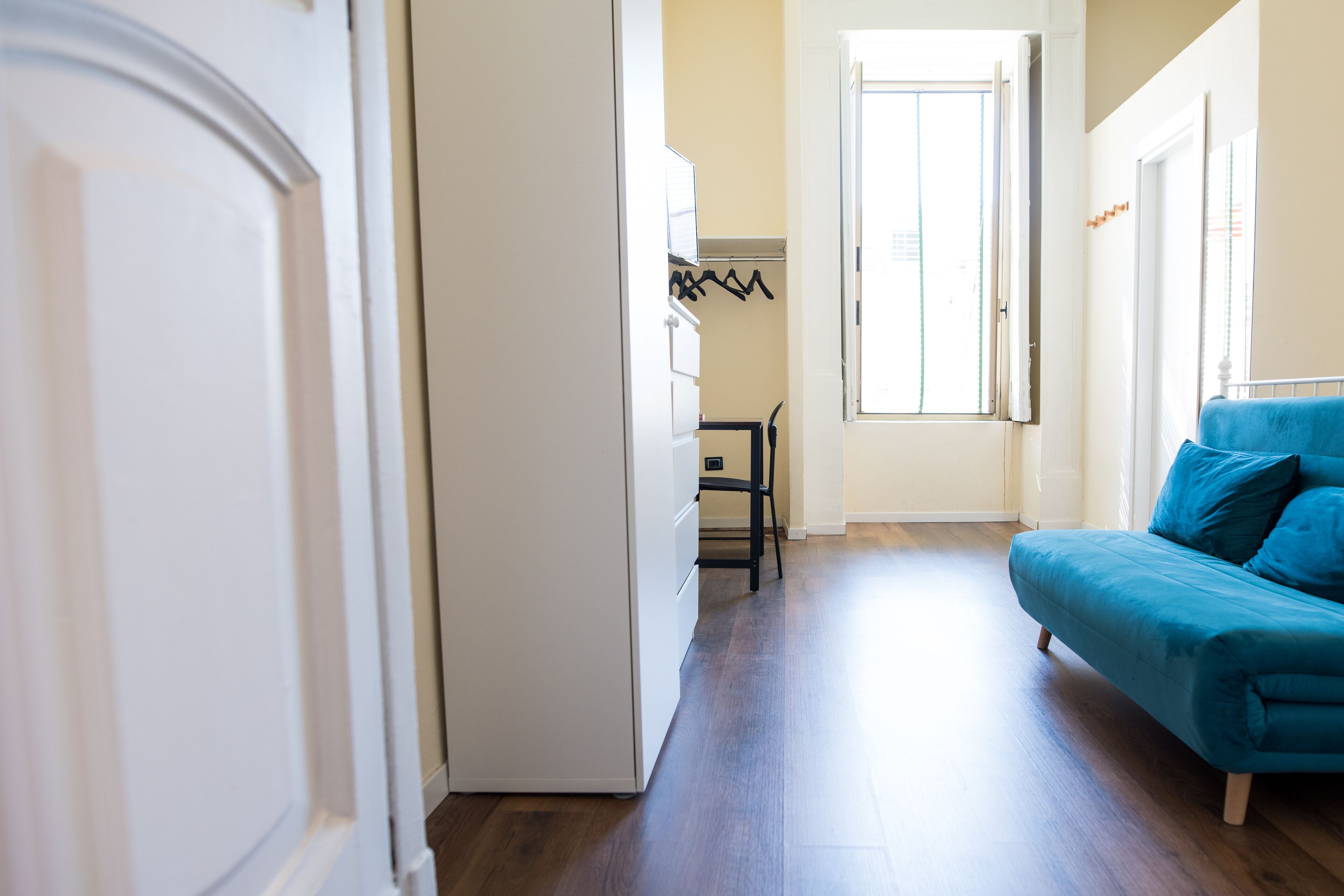 Un salon moderne avec un canapé bleu, un plancher en bois et une porte donnant sur une autre pièce.