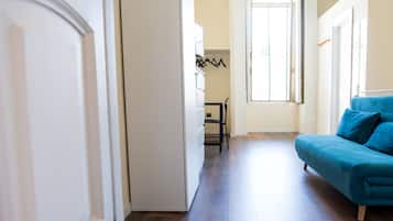 Un salon moderne avec un canapé bleu, un plancher en bois et une porte donnant sur une autre pièce.