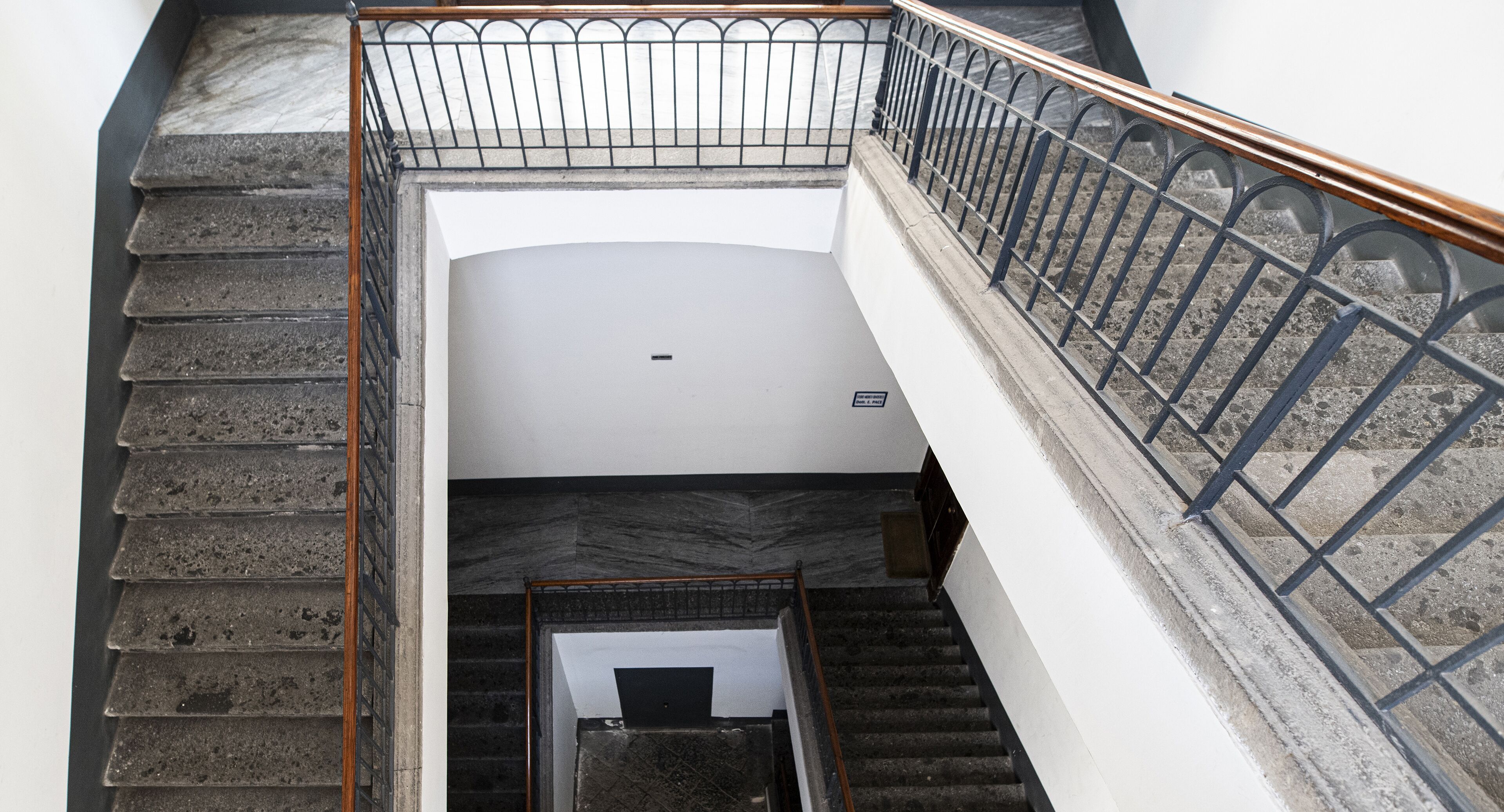 A staircase with a metal railing and a view of a door at the bottom.