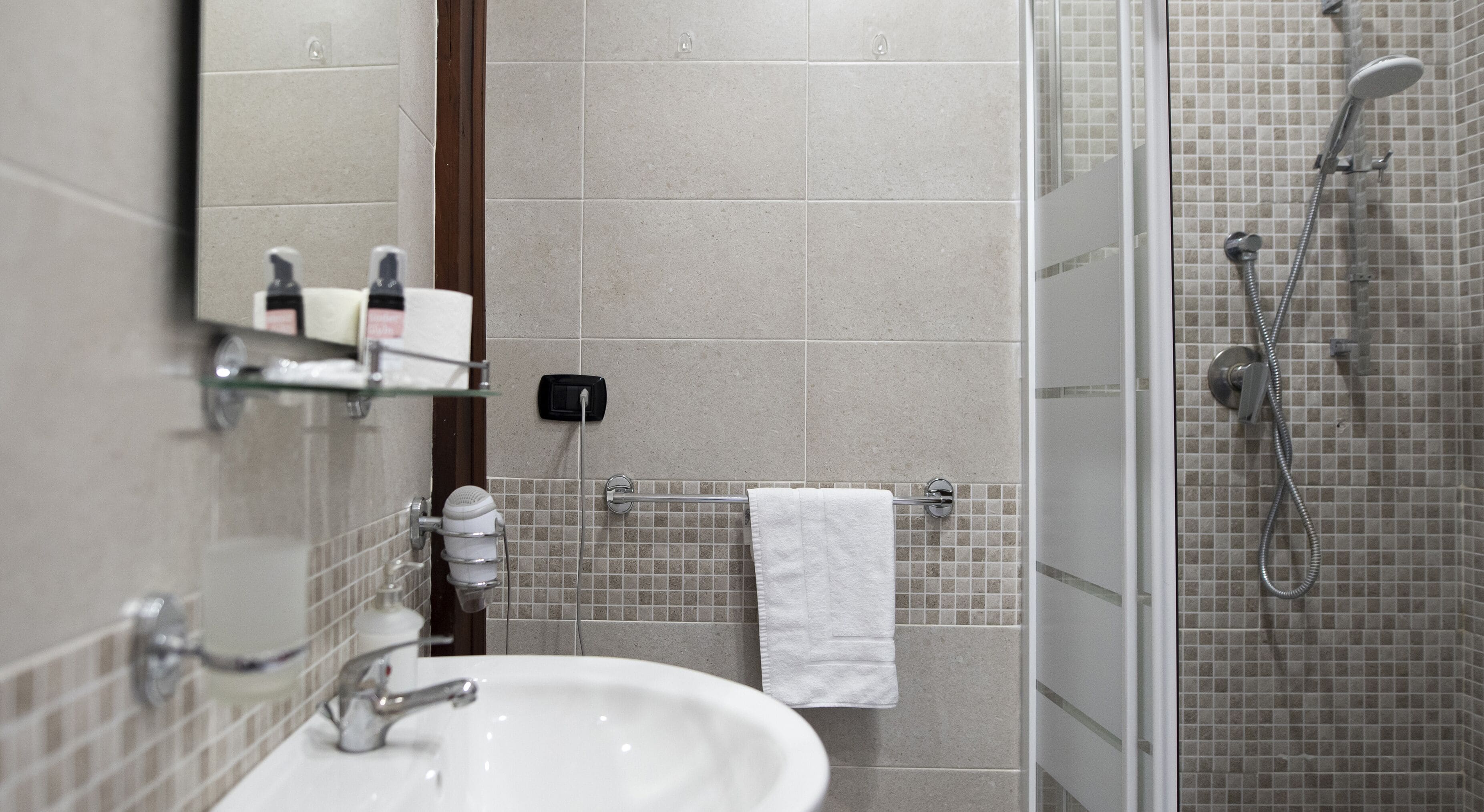 A bathroom with a sink, mirror, and shower.