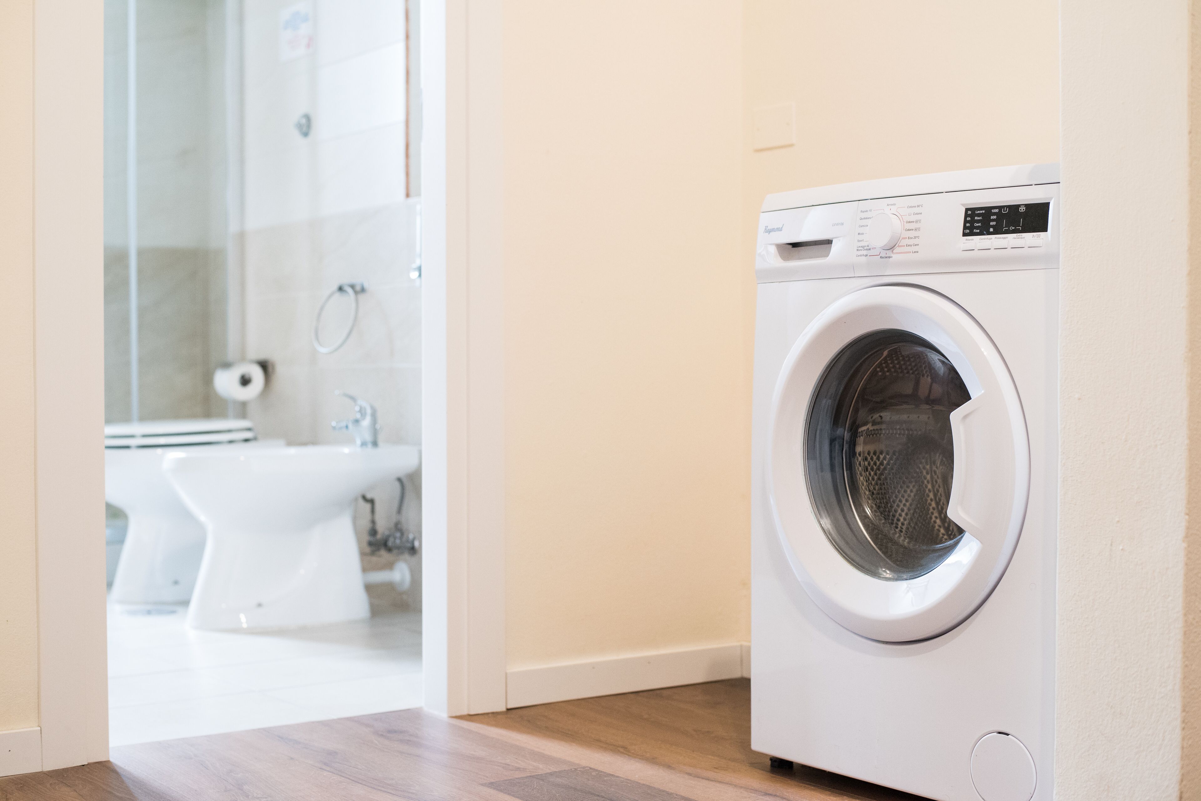 Un bagno moderno con una lavatrice bianca, un bidet e un water.