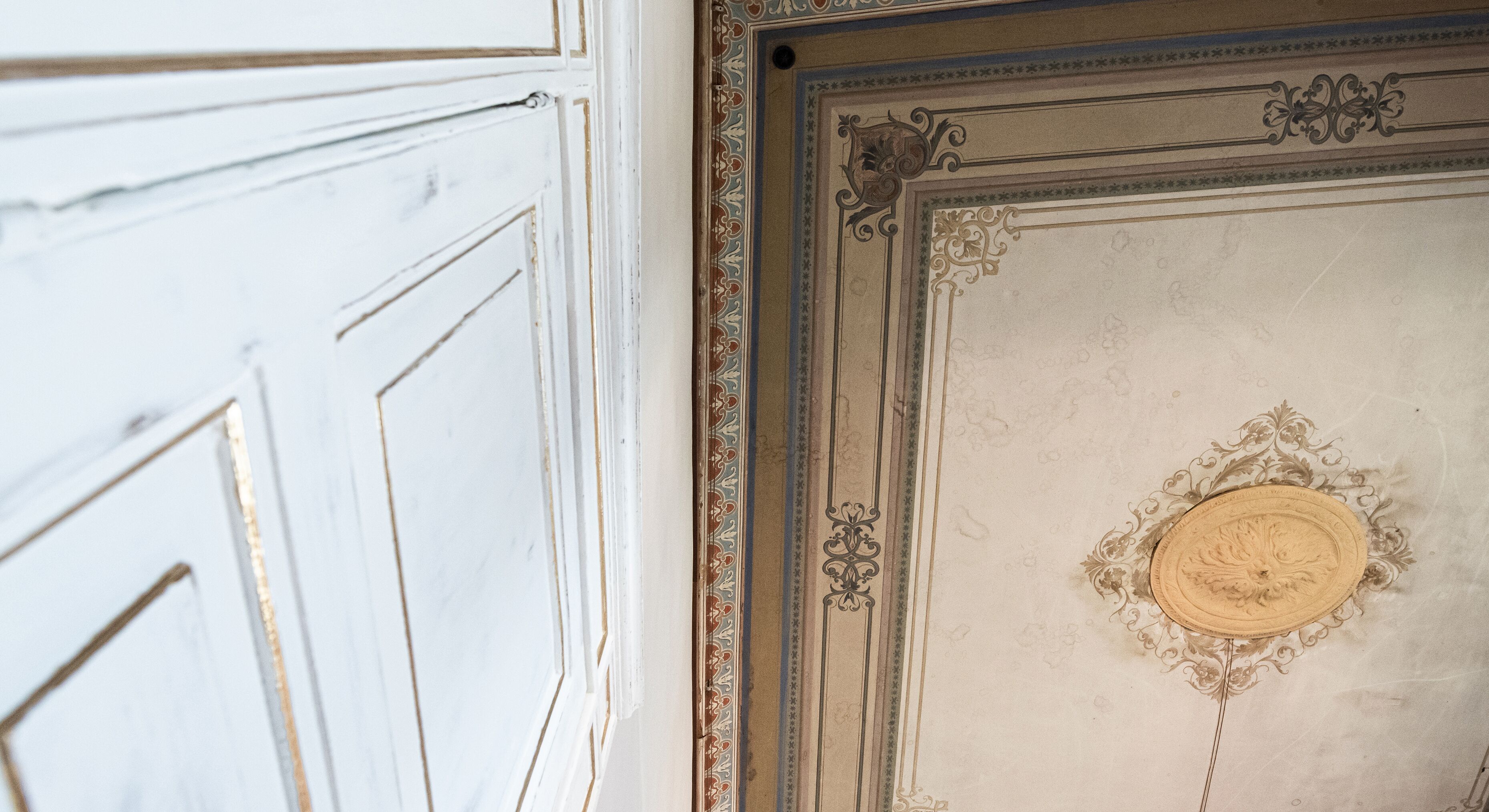 Primer plano de una pared blanca con molduras decorativas y un medallón circular.
