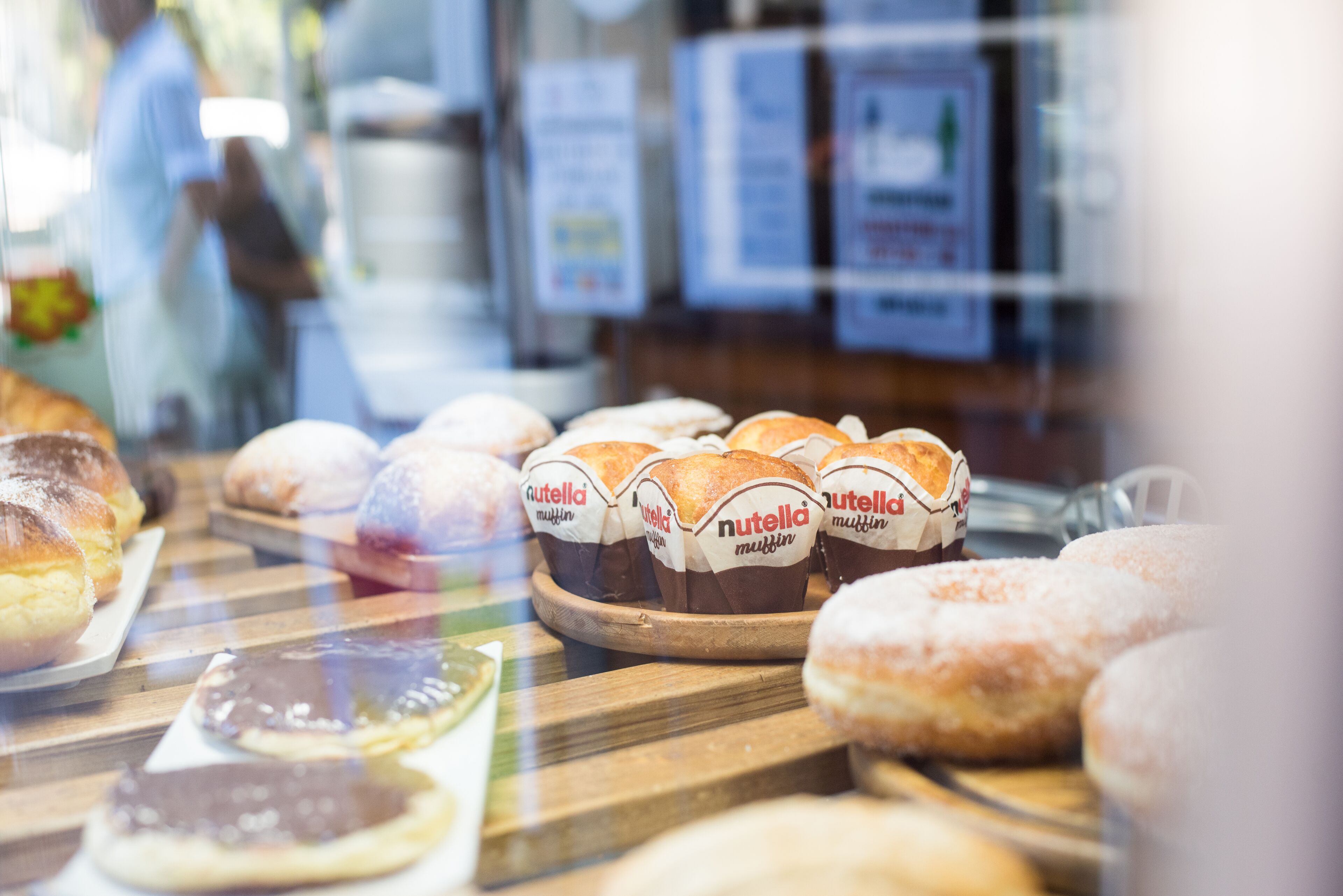 A bakery display with various pastries, including muffins and donuts, visible through a glass window.
