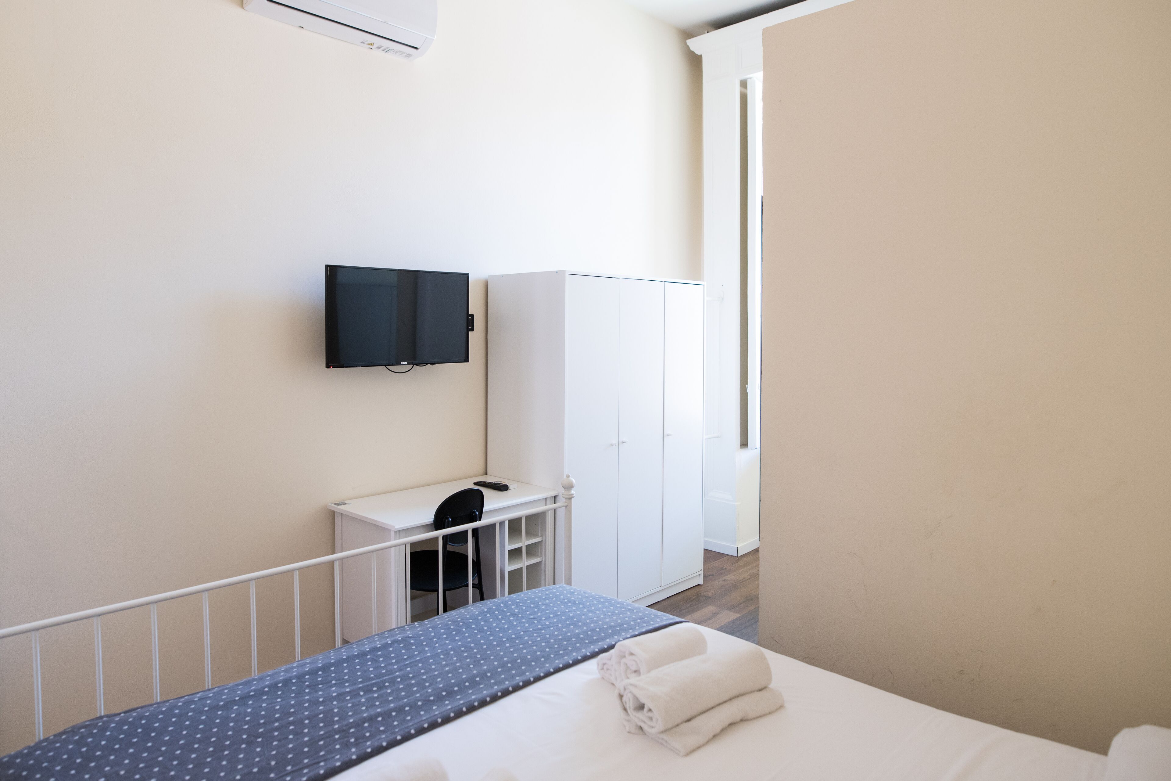 Una camera d'albergo con un letto, una scrivania, una sedia, un armadio e una televisione.