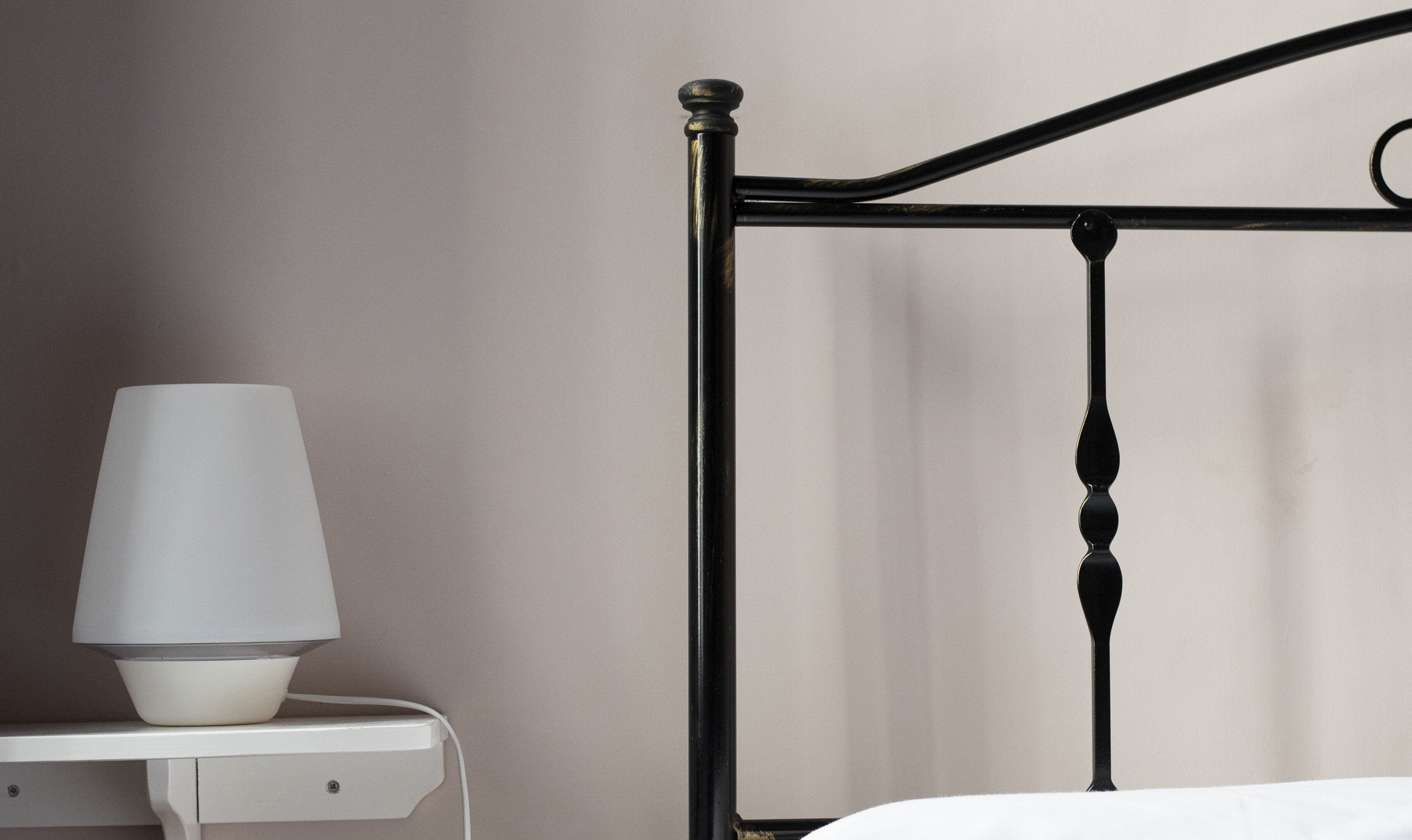 A bed with a metal frame and a bedside table with a lamp.