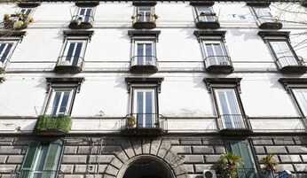 A building facade with multiple windows, some with balconies, and a central arched entrance.