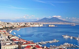 A coastal cityscape with a marina, buildings, and a mountain in the background.