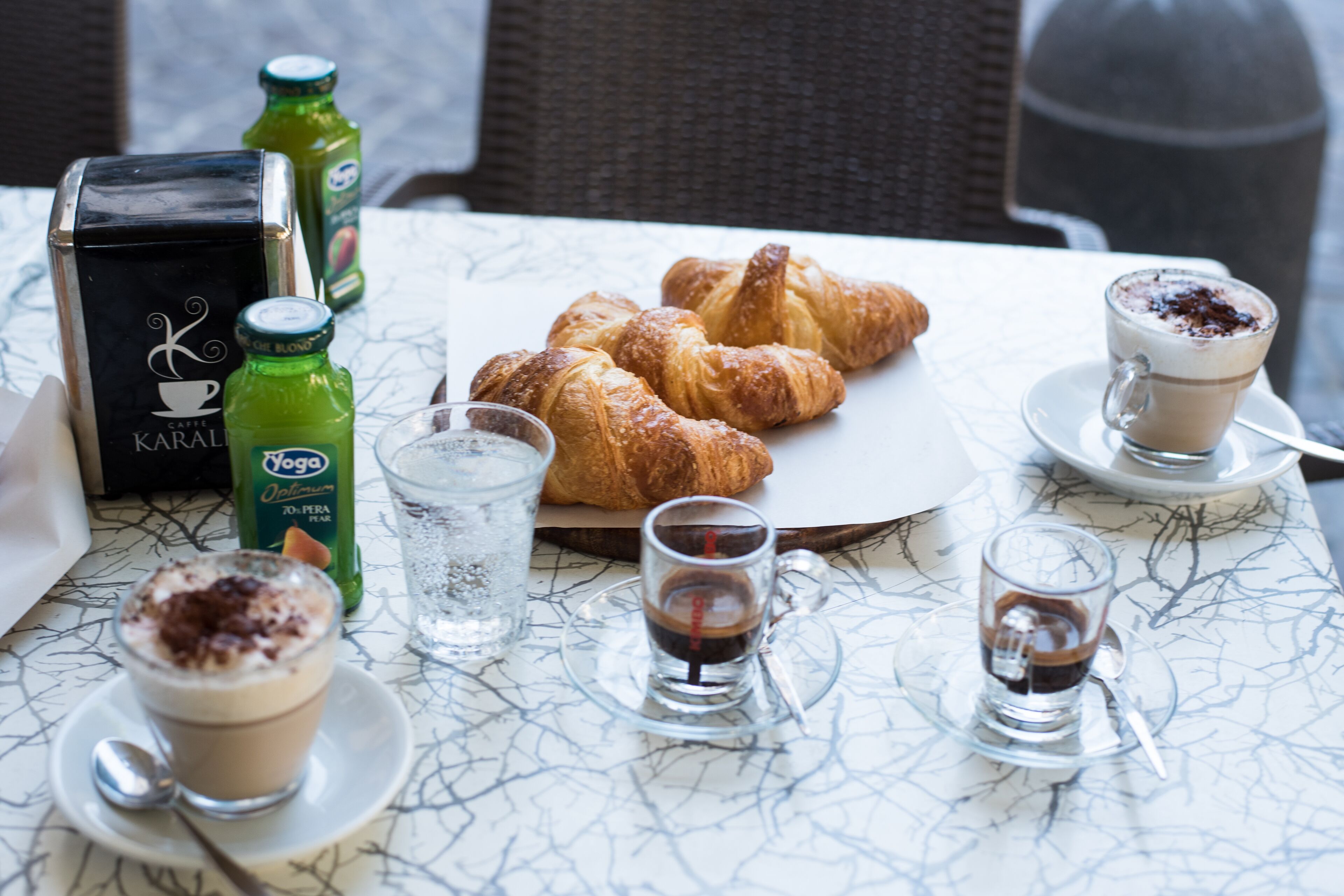 A table with croissants, coffee, and a box of Karalli coffee.