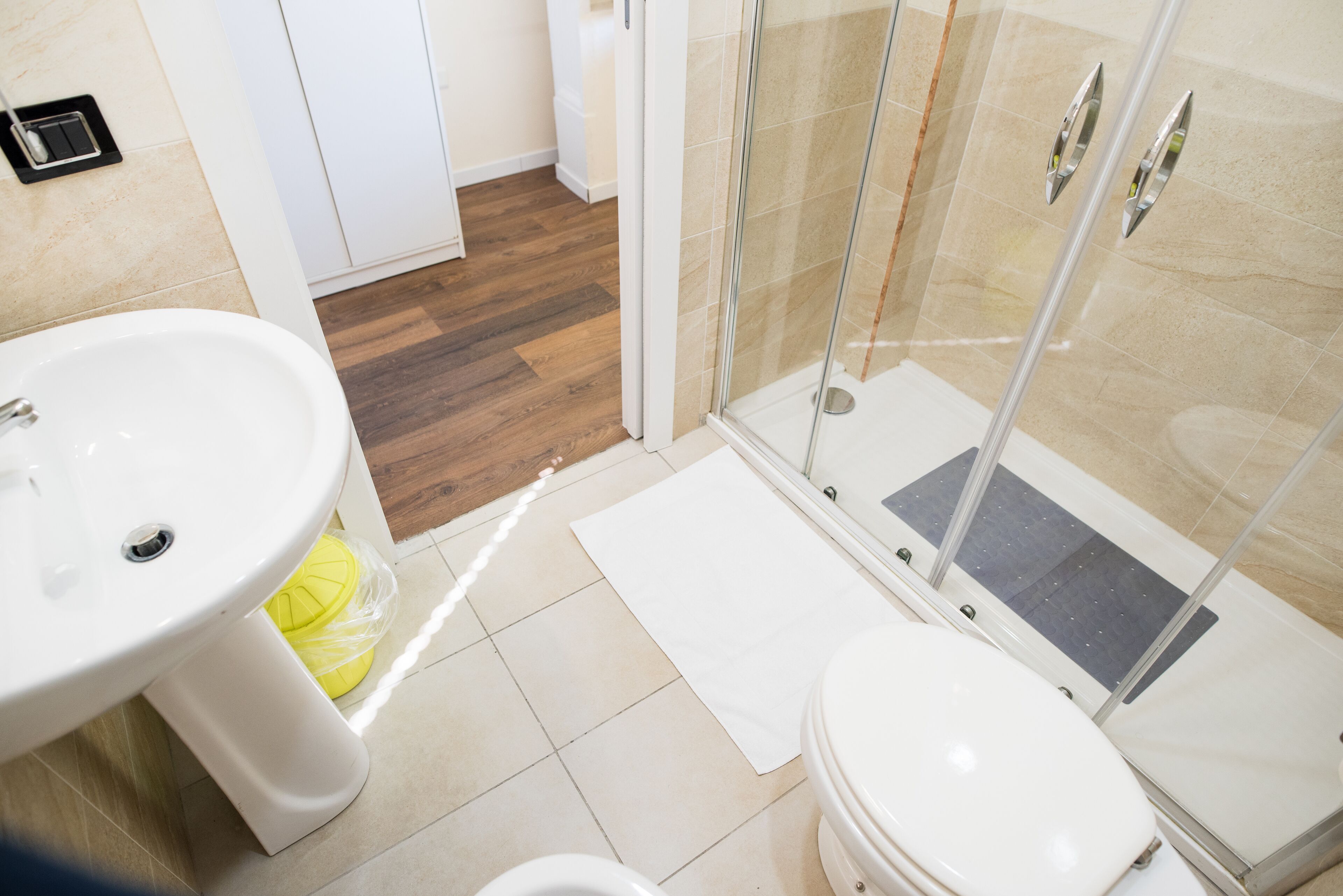 Un baño con lavamanos, inodoro y cabina de ducha con mampara de vidrio.