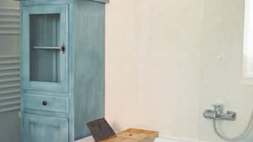 A bathroom with a light blue cabinet, a wooden tray, and a shower area.