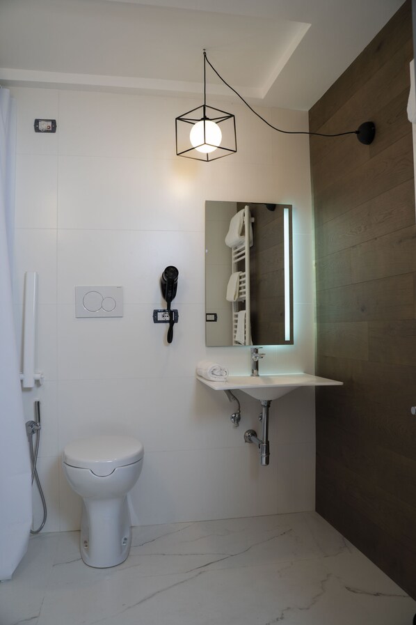 A modern bathroom with a white toilet, a sink, a hairdryer, and a mirror.
