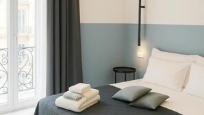 A modern bedroom with a bed, a nightstand, a lamp, and a view of the outside. - Rettifilo 311 (Naples)