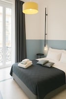 Una camera da letto moderna con un letto, un comodino, una lampada e vista sull'esterno.