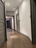 Un corridoio con pavimento in legno, pareti bianche e porte che conducono ad altre stanze.