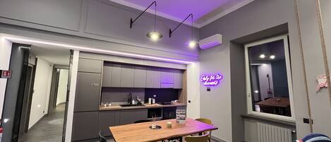 Una cocina moderna con armarios grises, una mesa de comedor de madera y un letrero de neón.