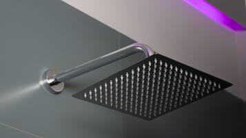 A modern shower with a square head and a metallic handle.