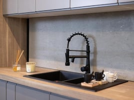 Una cucina con un rubinetto nero, un piano di lavoro in legno e un angolo caffè.