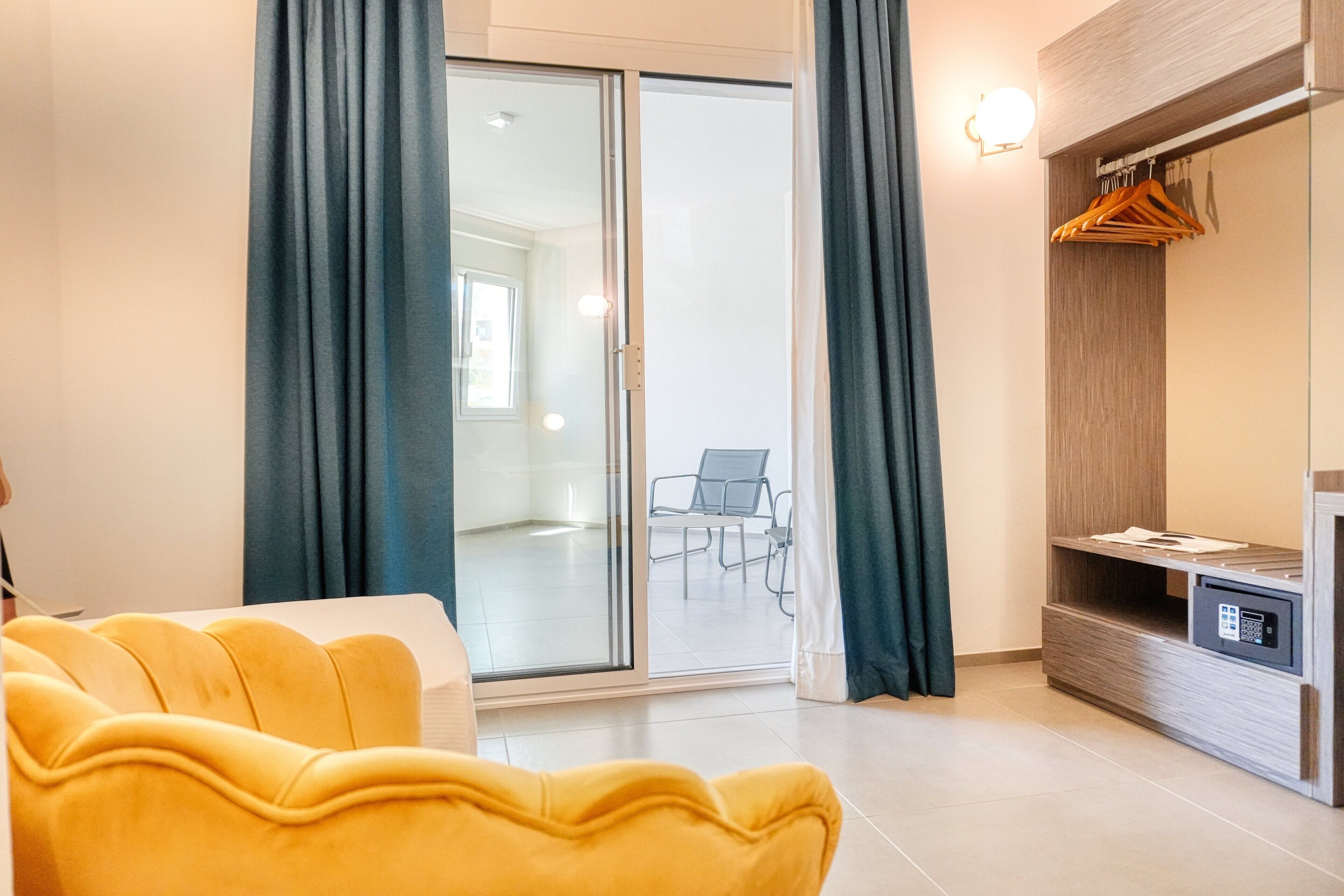 Una sala de estar moderna con un sofá amarillo, un ventanal corredero que da a un balcón y un mueble de madera con cerradura.