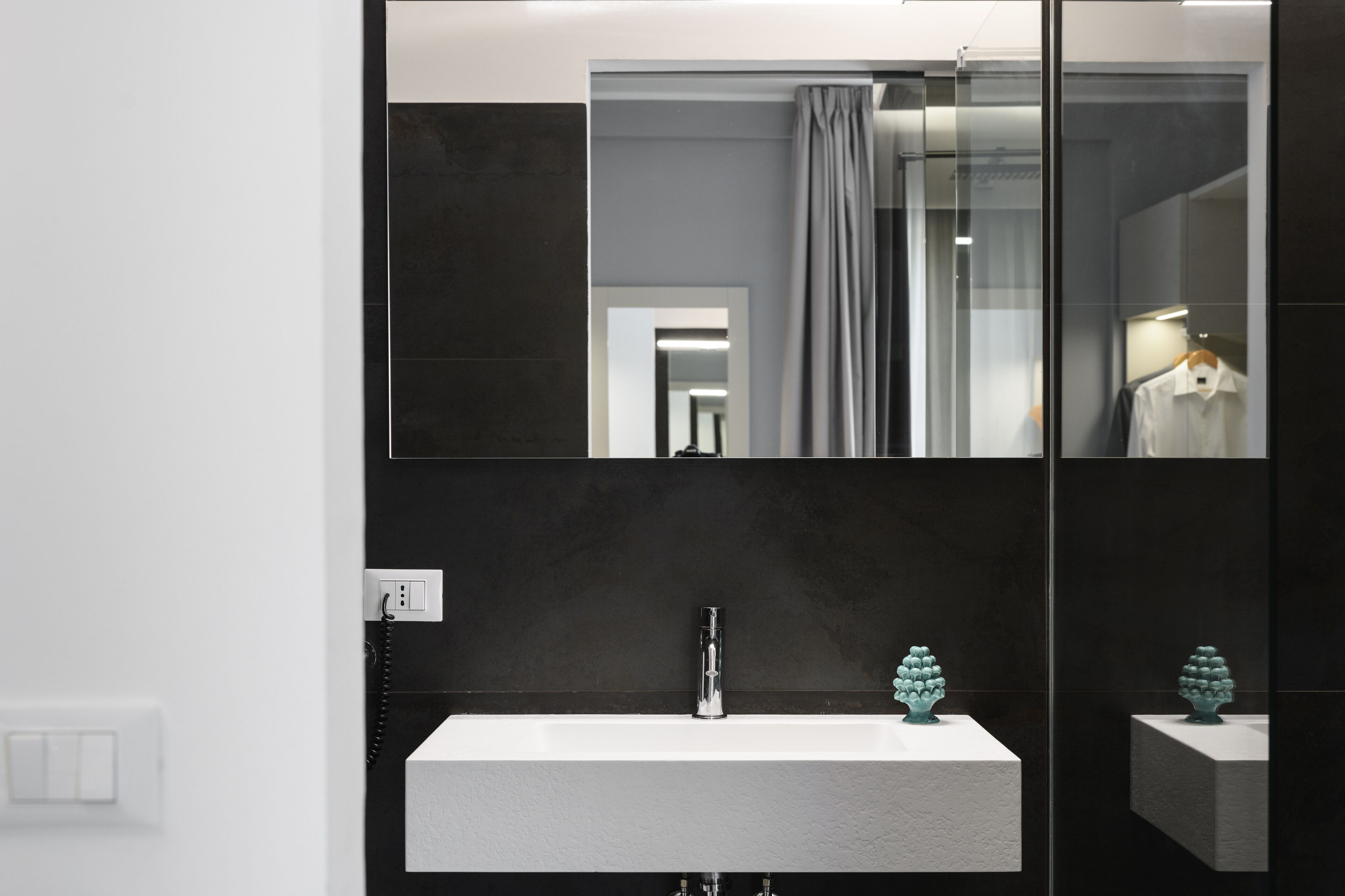 A modern bathroom with a large mirror, a white sink, and a towel rack.