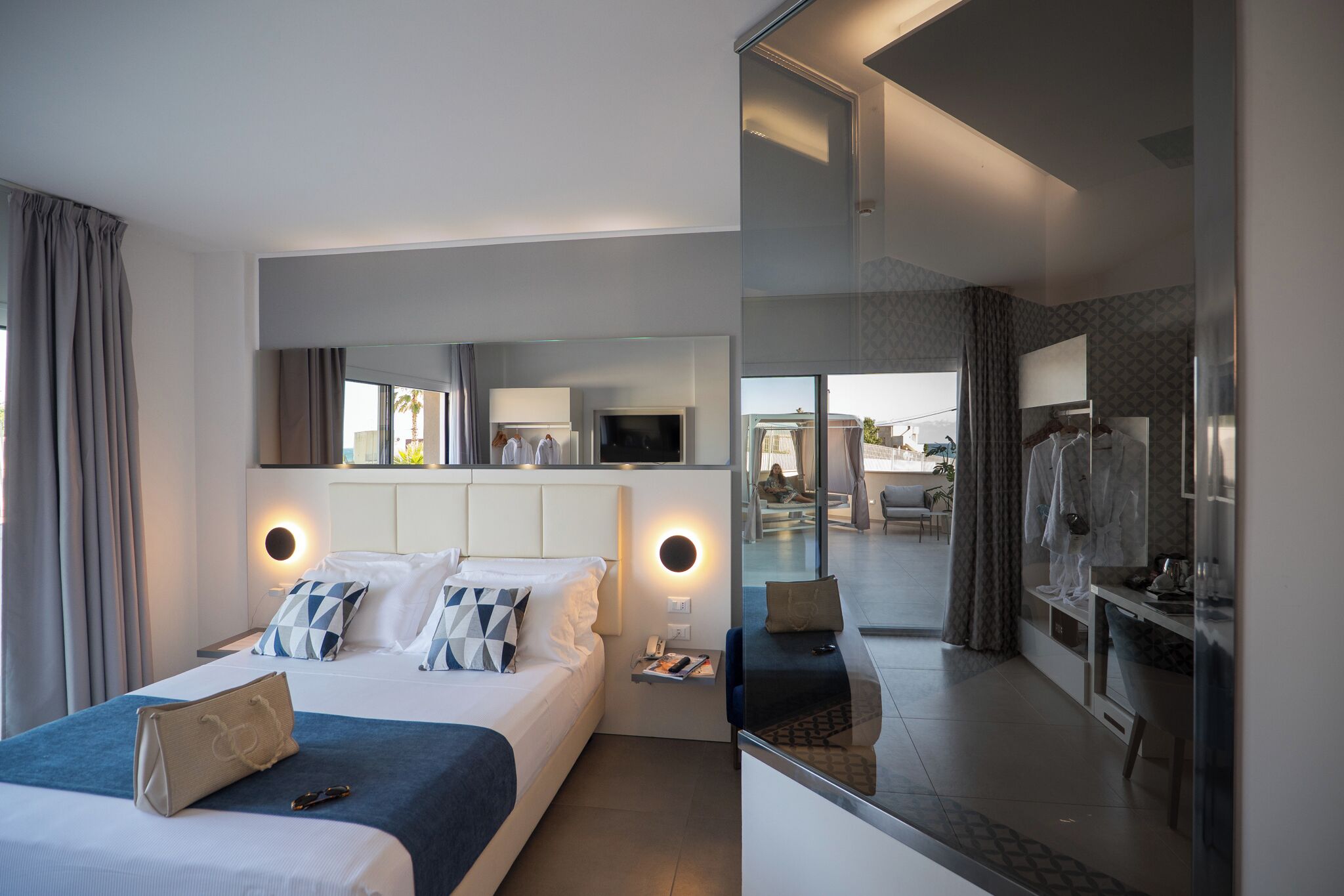 Una camera d'hotel moderna con un letto grande, comodini, una TV e vista sulla zona esterna.
