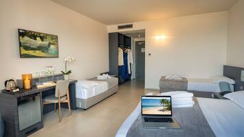 Ein Hotelzimmer mit Schreibtisch, zwei Betten, einem Laptop, einem Gemälde und einem Kleiderschrank.