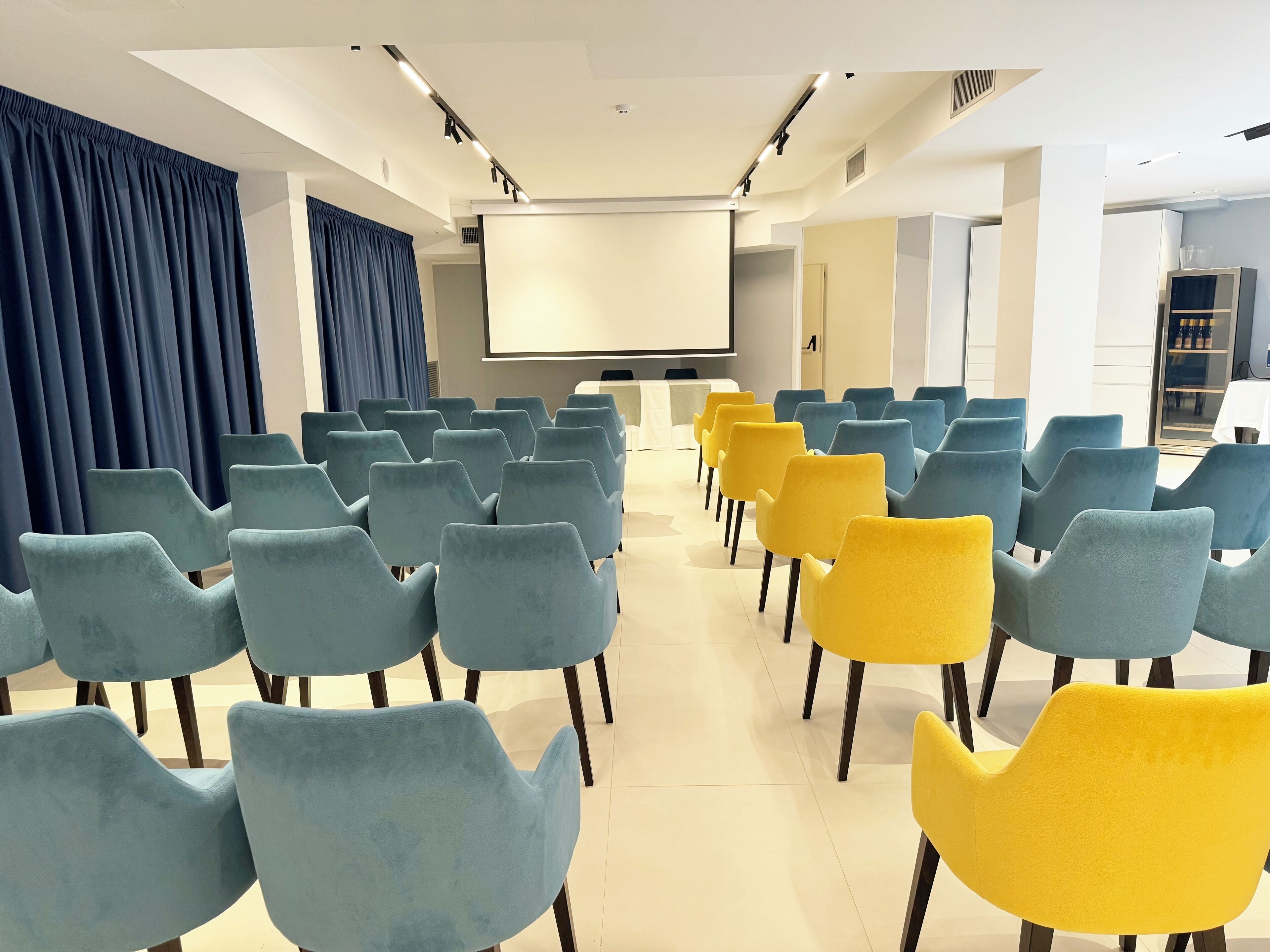 A conference room with rows of chairs, a projector screen, and a large window.