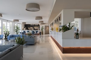 Egy modern szállodai előcsarnok, amelyben recepció, ülősarok és bár található.