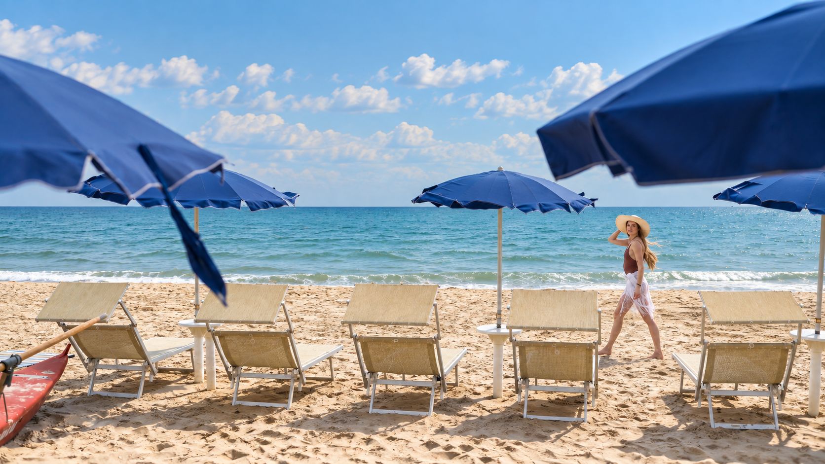 A beach with rows of sun loungers and umbrellas, a clear sky, and a calm sea.