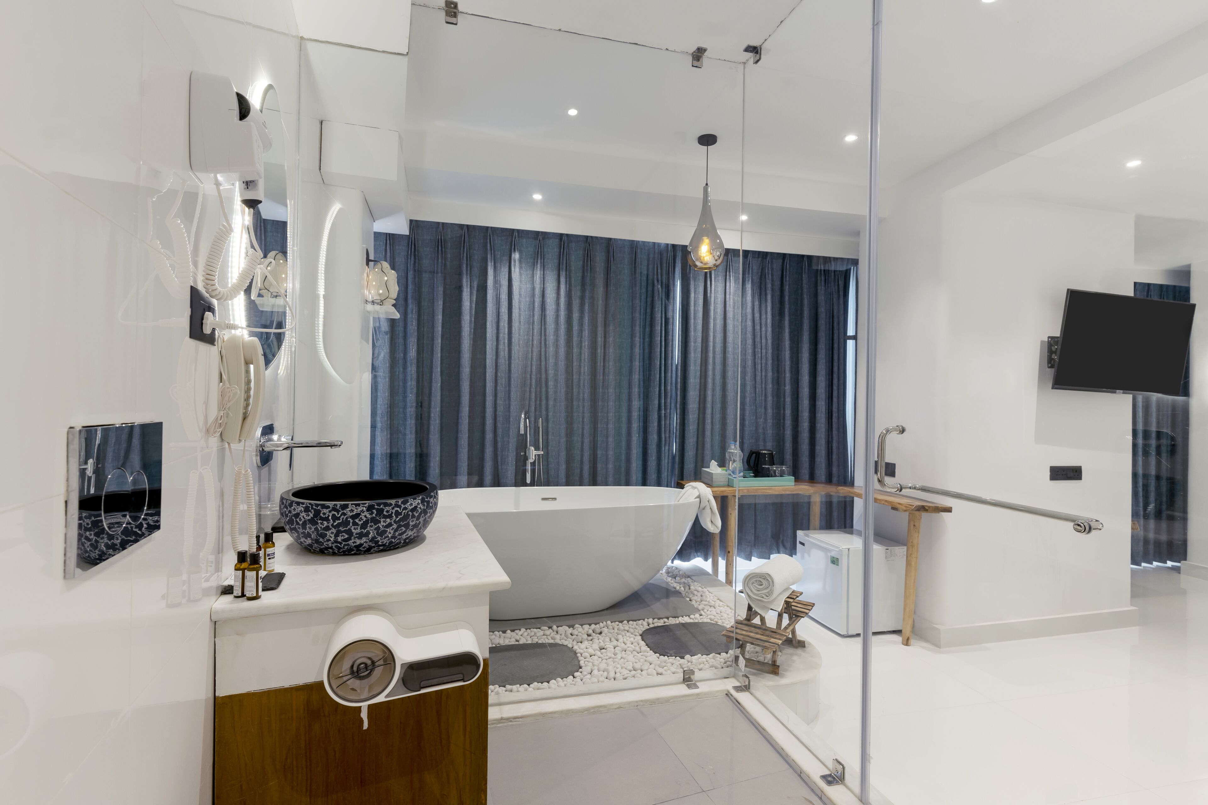 Een moderne badkamer met een vrijstaand bad, een grote spiegel, een wastafelmeubel met een wastafel en een douchecabine met glazen wanden.