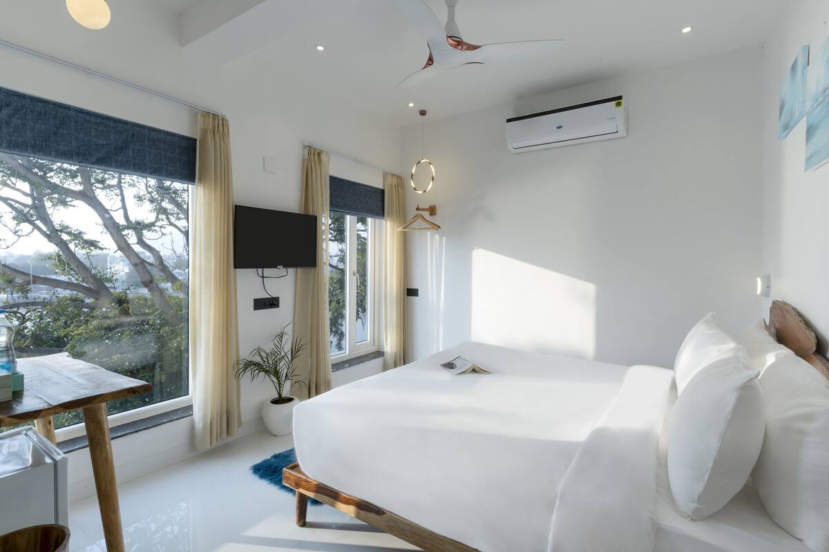 A modern bedroom with a large bed, a desk, and a TV.