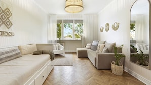 A modern living room with a sofa, a chaise lounge, a large mirror, and a hanging light fixture. - Elite Apartments Beachfront (Gdansk)
