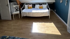 A bedroom with a sloped ceiling, a skylight, a bed with pillows, a chair, and a small table.