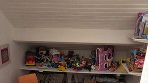 A children's playroom with a purple table and orange chairs, filled with toys and games.