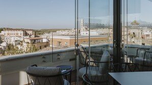 A balcony with a view of a cityscape, including a prominent tower and a dome. - Palazzo della Fontana (Matera)