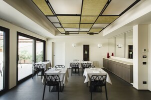 Un comedor moderno con mesas y sillas, una encimera de cocina y un amplio ventanal con vistas al exterior.