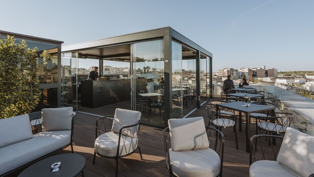An outdoor terrace with seating, a bar area, and a glass-enclosed space. - Palazzo della Fontana (Matera)