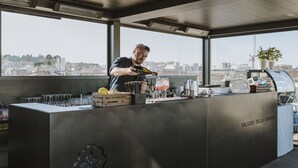 A bar area with a city view, a bartender, and a counter with various bar tools and glasses. - Palazzo della Fontana (Matera)