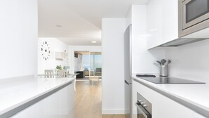 Een moderne keuken met witte kasten, een roestvrijstalen koelkast en een inbouwmagnetron.