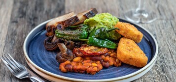 Un plato de comida con varios ingredientes, como frijoles, champiñones y un trozo de pan.